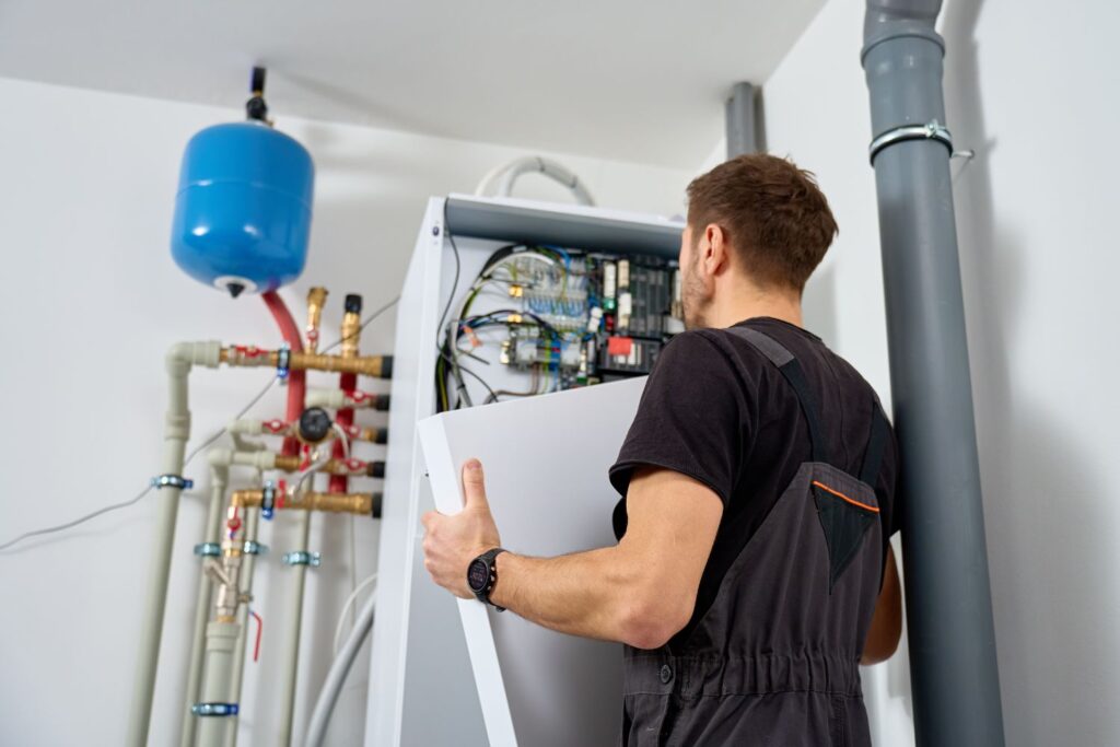 HVAC technician inspecting a boiler control panel and wiring in a utility room.
